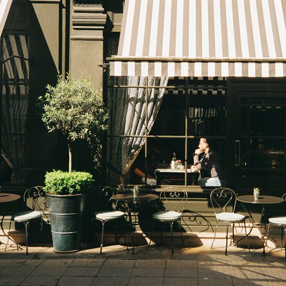 Library photo: a café terrace under a striped awning